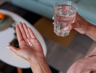 Person holding medication tablets and a glass of water